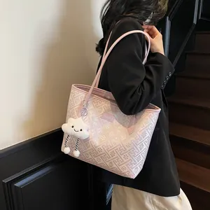 Dettaglio della borsa tote rosa con motivi geometrici e ciondolo a nuvola morbida