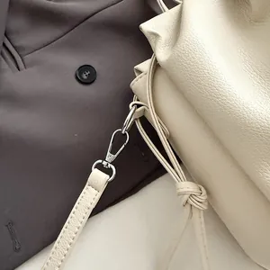 Macro view of cream white pleated bag with leather texture and silver lobster clasp detail