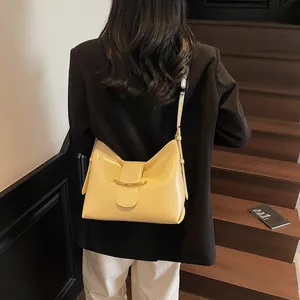 Detailed back view of a creamy yellow leather bucket bag worn with a black blazer