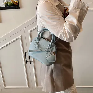 Sac coquille bleu clair à texture litchi avec chaîne argentée porté par un mannequin