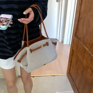 Detail of canvas tote bag with brown leather handles and side drawstring closure