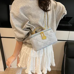Détail du sac matelassé bleu clair avec breloque rose dorée et bandoulière métallique