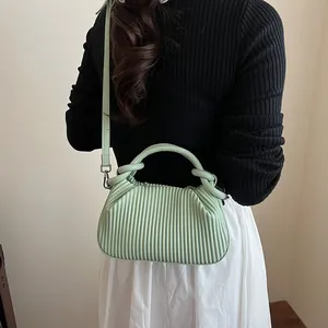 Détail d'un sac plissé vert menthe avec poignée cylindrique et bandoulière fine