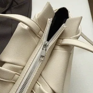 Macro view of lychee-textured leather and silver metal zipper on a beige cloud bag