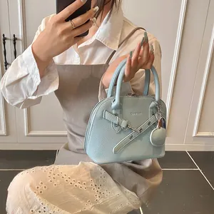 Détail du sac à main bleu clair en cuir grainé avec boucle métallique et breloque en cœur