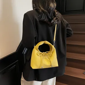 Detail of yellow pebbled leather handbag featuring a stylish knot handle and silver hardware