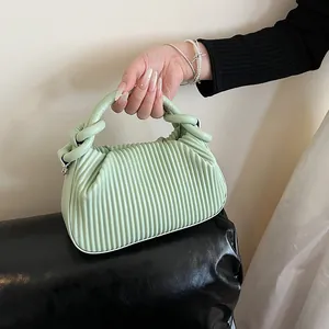 Détail du sac à main plissé vert menthe avec poignée nouée et accessoire chaîne en perles
