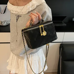 Vue détaillée du sac boîte matelassé noir avec chaîne dorée et breloques roses
