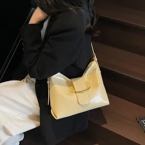 Detailed close-up of beige leather bucket bag featuring a unique gold curved buckle