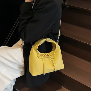 Detail of yellow lychee grain leather handbag featuring bow decor and silver metal hooks