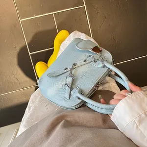 Détail du sac à main bleu clair texture litchi avec pendentif cœur et chaîne argent