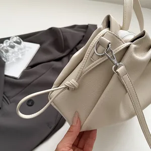 Detailed view of beige pleated leather cloud bag with silver hardware and knotted detail