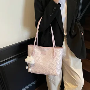 Dettaglio della borsa tote rosa geometrica con ciondolo a nuvola e placca logo