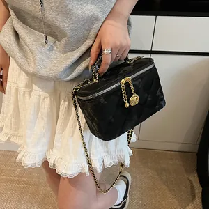 Détail du sac boîte noir matelassé avec une breloque de fermeture éclair rose dorée
