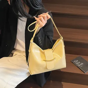 Detail of light yellow hobo bucket bag with a gold curved metal buckle and smooth texture