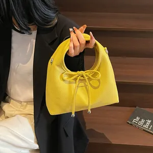 Detail of yellow lychee textured leather handbag with round handle and bow decoration
