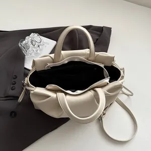 Top view showing spacious interior with black lining and leather folds of the cream bag