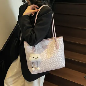 Dettaglio della borsa tote rosa con motivo geometrico e ciondolo a nuvola su legno