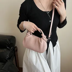 Détail du sac à main rose plissé avec texture verticale et finitions métalliques argent