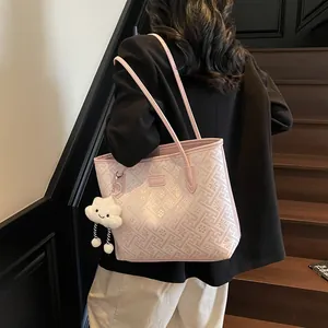 Dettaglio borsa tote rosa con rilievo floreale 3D e charm a nuvola sulla spalla della modella