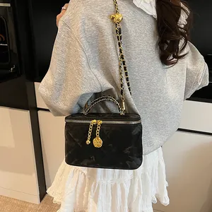 Détail de la trousse de toilette matelassée noire avec chaîne dorée et breloque camélia