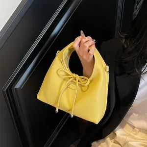 Detail of yellow lychee grain leather handbag with bow drawstring and silver metal charms