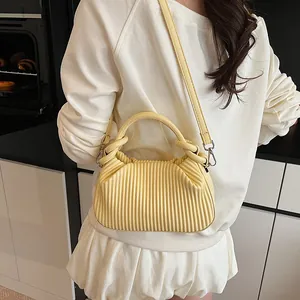 Détail montrant la texture plissée verticale et les ferrures argentées d'un sac jaune