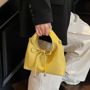 Close-up of yellow leather handbag with drawstring bow and silver metal beads