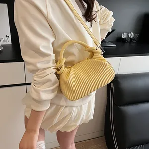 Détail du sac bandoulière plissé jaune avec textures verticales et fine bandoulière