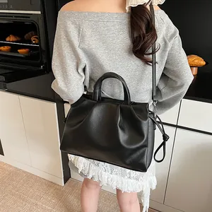 Detail of black pleated cloud bag with soft leather texture and drawstring side ties