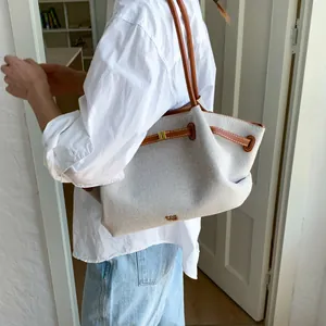 Detail of canvas tote bag with brown leather trim and golden Paris logo engraving