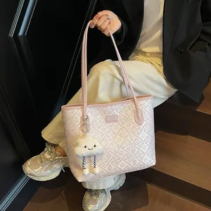 Dettaglio della borsa tote rosa intrecciata geometricamente con ciondolo a nuvola bianca