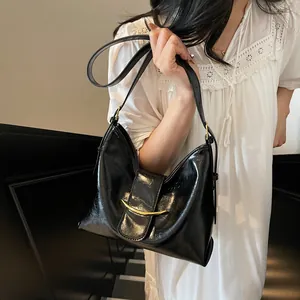 Detailed view of black patent leather bucket bag featuring a crescent gold metal buckle