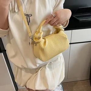 Gros plan du sac bandoulière plissé jaune montrant les textures et les détails métalliques