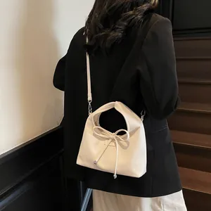 Detail of cream white leather handbag with lychee texture and bow tie decoration
