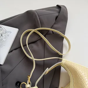 Detail of woven texture beige shoulder bag with golden buckle and sleek leather strap