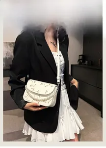 Detailaufnahme der weißen Handtasche mit Blumenstickerei und eleganter Perlenkette