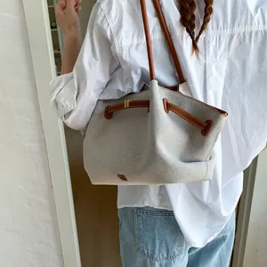 Detail of a large canvas tote bag with brown leather handles and drawstring closure