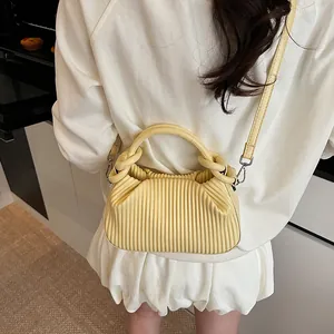 Détail macro de la texture plissée verticale sur le sac nuage bandoulière jaune clair