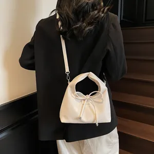 Detail of off-white lychee grain leather handbag with bow knot and metal chain strap