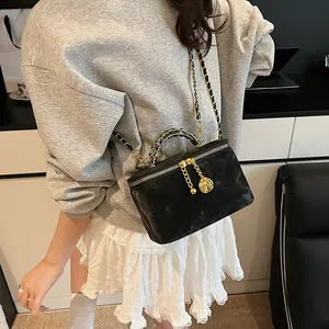 Détail du vanity bag matelassé noir avec breloque camélia doré et bandoulière