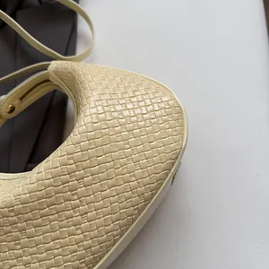 Close-up of cream woven leather texture and side stitching on the crescent shoulder bag