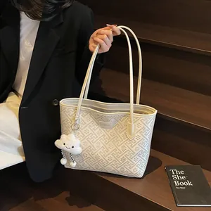 Dettaglio della borsa tote bianco avorio con motivi geometrici e ciondolo a nuvola