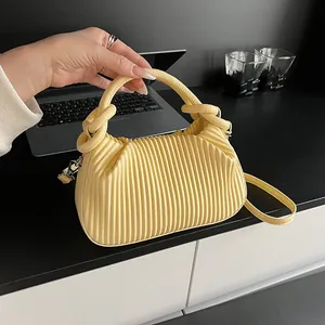 Détail du sac à main plissé jaune avec rayures verticales et poignée nouée