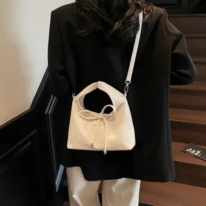 Close-up of cream bow-knot handbag with lychee texture leather on a model's back