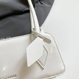 Detail shot of white patent leather bowling bag with knotted strap and silver zipper