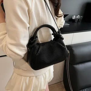 Gros plan détaillé sur la texture plissée verticale et le cuir PU souple de ce sac noir