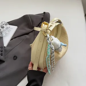Detail of woven texture on cream crescent bag with plush charm and gold hardware