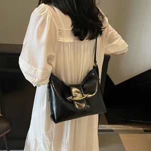 Detail of glossy black leather bucket bag with elegant crescent golden buckle clasp