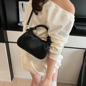 Détail d'un sac à main noir à plis verticaux avec bandoulière et poignée ronde